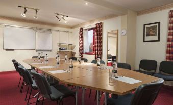 a conference room with a long wooden table , chairs , and water bottles arranged for a meeting at Days Inn by Wyndham Tewkesbury Strensham