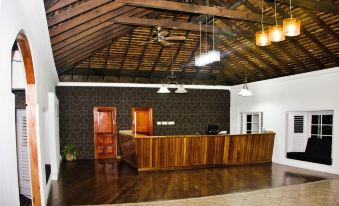 a room with a wooden reception desk , two potted plants , and hanging lights under a covered ceiling at Grand Hotel Excelsior Port Royal