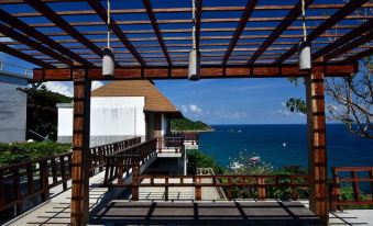 a wooden deck overlooking the ocean , with a table and chairs set up for outdoor dining at Sai Daeng Resort