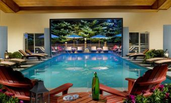 an indoor pool surrounded by wooden chairs , with a large screen displaying an image of the ocean at The Lodge at Jackson Hole