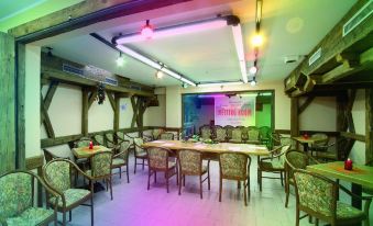 a large room with multiple tables and chairs , a projector screen , and neon lights on the ceiling at Hotel Dolomiti Schloss