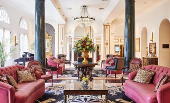 a luxurious hotel lobby with red couches , a marble coffee table , and ornate columns , decorated with flowers at Bourbon Orleans Hotel