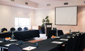 a conference room set up for a meeting , with chairs arranged in rows and a projector on the wall at The Clan Terrigal