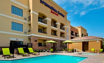 an exterior view of a springhill suites hotel with a swimming pool in the foreground at SpringHill Suites Madera