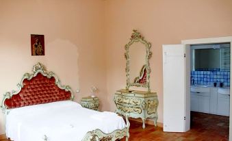 a luxurious bedroom with a red and white bedspread , ornate furniture , and an ornate mirror at Villa Luisa