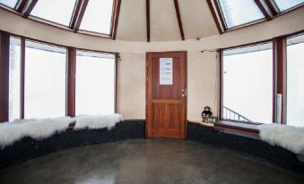 a room with a large window and a wooden door , featuring a black windowsill and stone floor at Klettar Tower Iceland