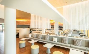 a modern restaurant with multiple dining tables and chairs , as well as a bar area at Hey Lou Hotel Frankfurt Airport