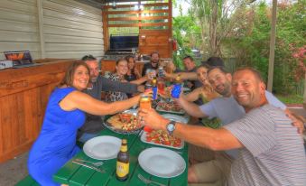 a group of people are sitting at a table with food and drinks , toasting with their drinks at Hi-Way Motel Grafton - Contactless