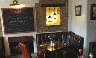 a cozy dining room with a leather couch , a dining table , and a chalkboard on the wall at The Old Mill