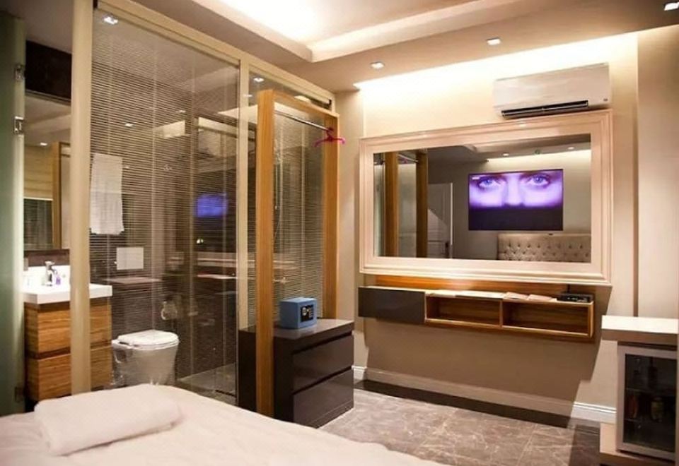 a modern hotel room with a large bed , tv , and a bathroom with a glass door at Upper House Hotel