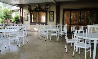 a room with white chairs and tables , a door , and a window covered by a curtain at Bella Vista Resort