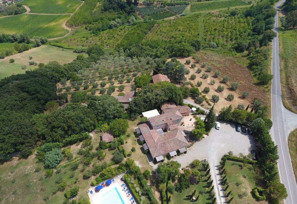 an aerial view of a large house surrounded by trees and a swimming pool , with a pool in the foreground at Antico Borgo Il Cardino