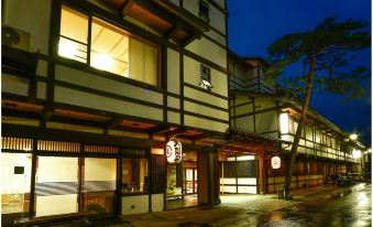 a nighttime view of a traditional japanese building with its lights on , under a clear blue sky at Osakaya Ryokan