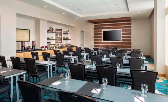 a large conference room with rows of chairs arranged in a semicircle , and a television mounted on the wall at Residence Inn by Marriott Boston Watertown