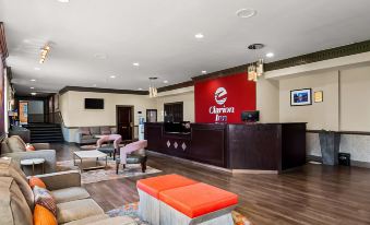 a hotel lobby with a large red sign on the wall , a reception desk , and several chairs at Clarion Inn Falls Church-Arlington