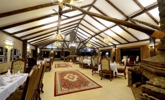 a large dining room with wooden tables and chairs , surrounded by a brick wall and ceiling at Ngorongoro Oldeani Mountain Lodge