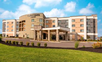a large hotel building with multiple parking spaces and an outdoor seating area , surrounded by a grassy field at Courtyard Cleveland Elyria