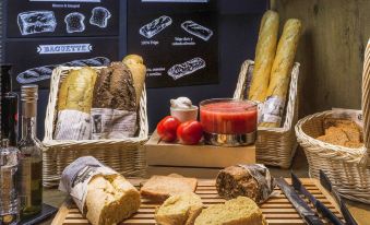 a table with a variety of breads and pastries , including a loaf of bread in a basket at Ibis Strasbourg Centre Historique