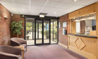 a hotel lobby with a reception desk , chairs , and an open door leading to the outside at Days Inn by Wyndham Chesterfield Tibshelf