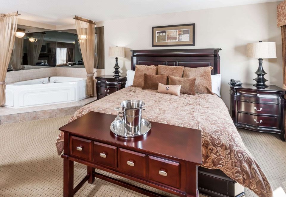 a luxurious bedroom with a king - sized bed , a bathtub in the corner , and a dresser nearby at Ramada by Wyndham High River