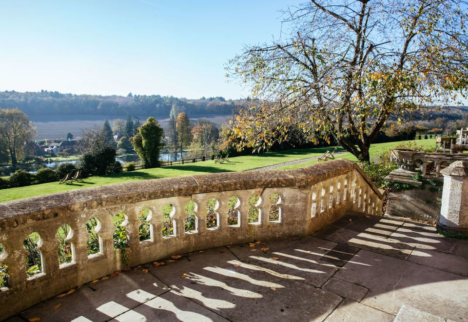 a stone staircase with trees and shrubs on either side , leading down to a river valley at De Vere Latimer Estate