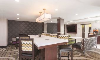 a modern dining room with multiple tables and chairs , a tv , and a chandelier hanging from the ceiling at La Quinta Inn & Suites by Wyndham Knoxville North I-75