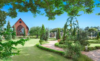 a beautiful garden with green grass , trees , and flowers , as well as a red brick building in the background at Sheraton Grande Tokyo Bay Hotel