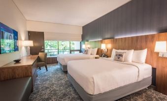 a modern hotel room with two beds , nightstands , and large windows offering views of the outdoors at Inn at Villanova University