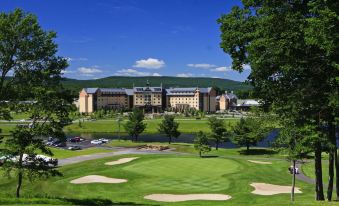 a large building with a green lawn and golf course in front of it , under a clear blue sky at Mount Airy Casino Resort - Adults Only 21 Plus
