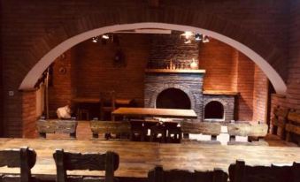 an old brick building with a fireplace in the middle of it , surrounded by a dining room with wooden tables and chairs at Orion Hotel