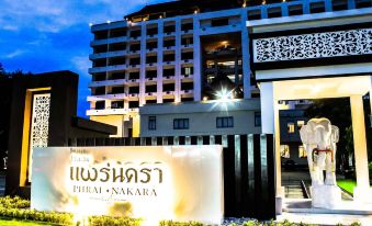 "a large hotel with a sign that says "" phem nakara "" is illuminated at night in front of the building" at Phrae Nakara Hotel