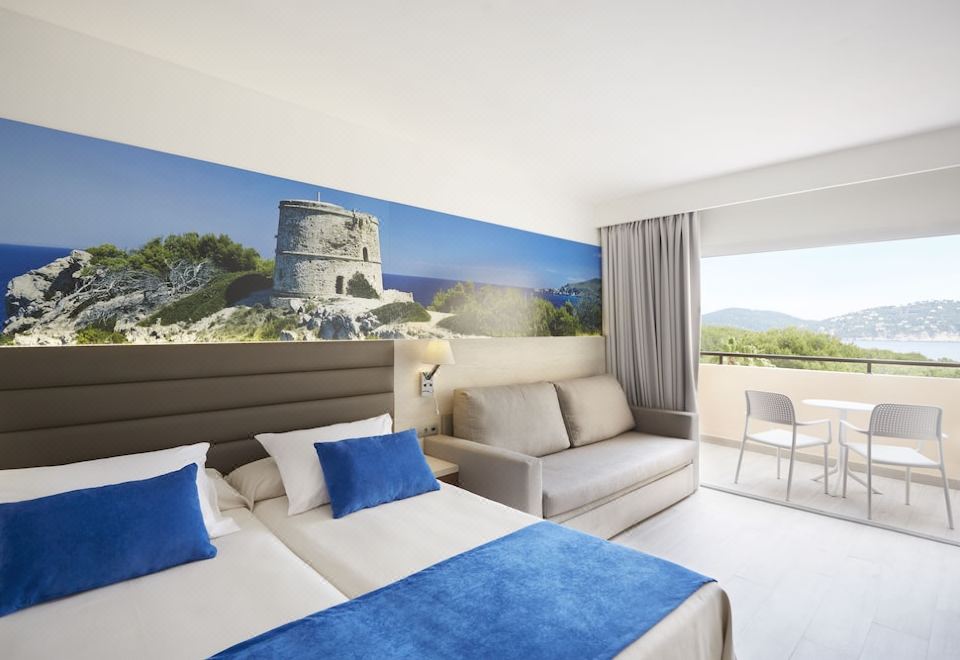 a modern hotel room with a large bed , couch , and balcony , featuring a panoramic view of the sea and mountains at Invisa Hotel Club Cala Blanca