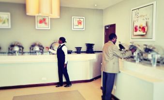 two men are standing in a hotel lobby , one of them is checking in at the front desk at Grand Palace Hotel Mzuzu
