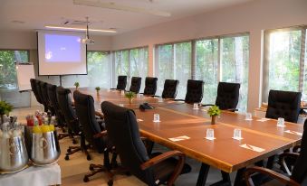 a large conference room with multiple rows of chairs arranged in a semicircle around a long wooden table at Joali Maldives