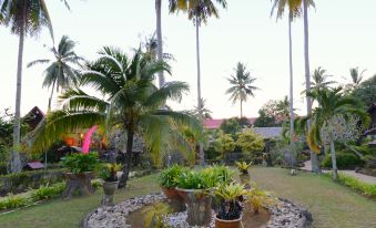 a lush green garden with various plants and trees , including palm trees , creating a serene and inviting atmosphere at Lavilla by Holiday Villa Cherating