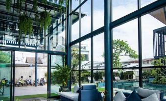 a modern , spacious living room with large windows and a blue couch , surrounded by plants and outdoor furniture at Blue Lagoon Hotel