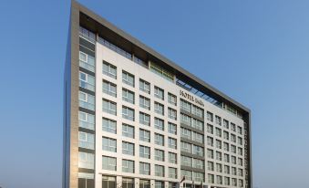 a modern building with a white exterior and large windows , located on a busy street at Hotel Baia