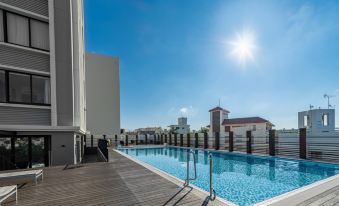 a large swimming pool with a wooden deck and sun shining in the background , surrounded by buildings at Hyatt Regency Naha, Okinawa