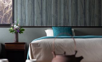 a bed with blue sheets and a white pillow is in a room with a vase of flowers on the nightstand at Fuefukigawa Onsen Zabou