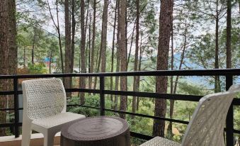 a balcony overlooking a forested area , with a table and chairs placed on the balcony at Hotel Bliss
