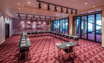 a large conference room with red carpeted floors , multiple rows of tables , and rows of chairs at Scandic Falkoner