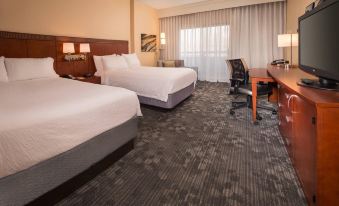 a hotel room with two beds , a desk , and a window , all well - lit by the lights on at Courtyard New Carrollton Landover