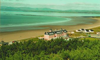 aerial view of a resort with a large building , a beach , and a body of water at Sandhouse Hotel