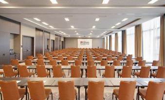 a large conference room with rows of chairs arranged in a semicircle , ready for an event at Hilton Garden Inn Zurich Limmattal