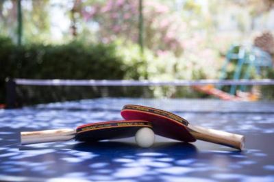 two red ping pong paddles resting on a blue table , with one ping pong ball lying on the table at Hotel Summery