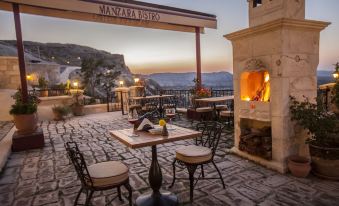 a stone patio with a dining table and chairs , as well as a fireplace in the background at Kayakapi Premium Caves Cappadocia