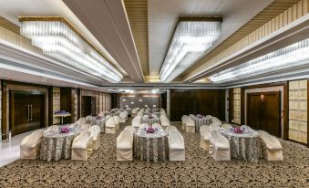a large , well - lit conference room with numerous round tables and chairs arranged for a formal event at The Regenza by Tunga