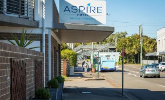 a bus is parked on the side of a street with a hotel sign above it at Aspire Mayfield