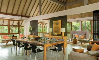 a modern living room with wooden floors , a large dining table set for a meal , and several chairs at Four Seasons Resort Maldives at Landaa Giraavaru