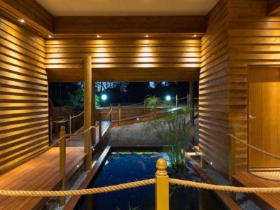 a wooden deck with a staircase leading up to a pond , surrounded by trees and plants at The Swan Valley Retreat